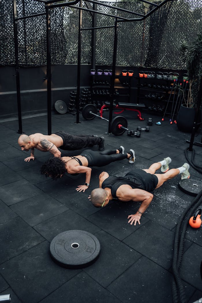 Three adults performing push-ups at an outdoor gym in Mexico City, showcasing strength and teamwork.